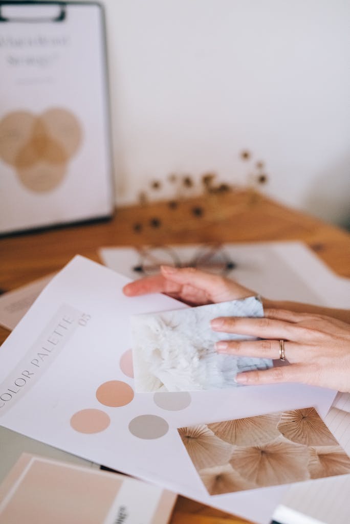 Designer selecting color palettes for a creative project with materials on a wooden table.